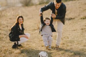 A family playing soccer in the field, promoting physical activity and social interaction for children with autism. - Autism Connect