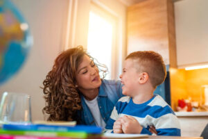 A woman and a boy sitting at a table with books, focusing on the emotional needs of children on the autism spectrum.