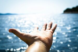 5) A hand reaching out to the water, symbolizing connection and exploration. - Autism Connect 