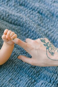 3) A baby with a tattoo on its hand laying on a blanket. - Autism Connect 