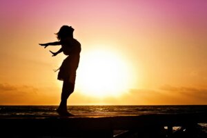 A woman standing by the ocean at sunset, symbolizing empowerment and self-discovery in managing ADHD in women.