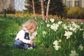 Child enjoying flowers in a garden designed as calming outdoor spaces for autism-friendly living.